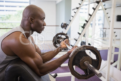 Muscular man lifting barbell in gym