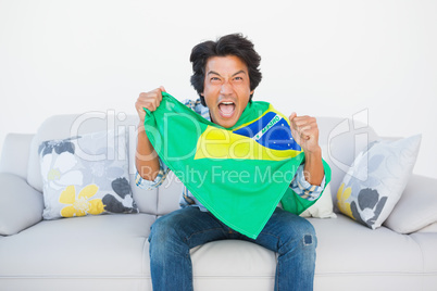Football fan cheering and holding brazil flag