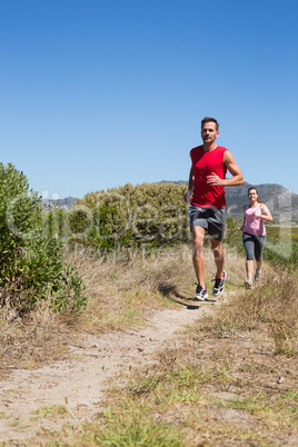 Active couple jogging on country terrain