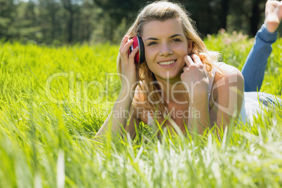 Pretty blonde lying on grass with headphones around neck