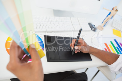 Designer working at desk using digitizer and colour sample