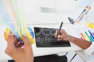 Designer working at desk using digitizer and colour sample