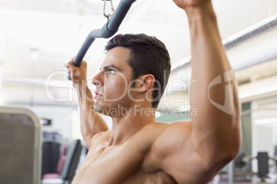 Muscular man exercising on a lat machine in gym