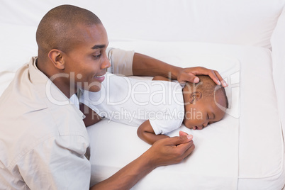 Adorable baby boy sleeping while being watched by father