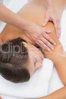 Attractive woman receiving shoulder massage at spa center