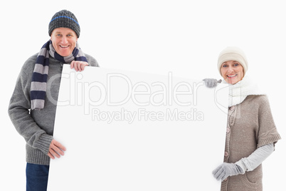 Mature couple in winter clothes holding card