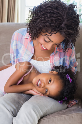 Cute daughter lying across mothers lap