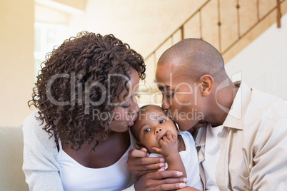 Happy young parents spending time with baby on the couch