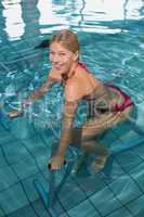 Fit blonde using underwater exercise bike smiling at camera