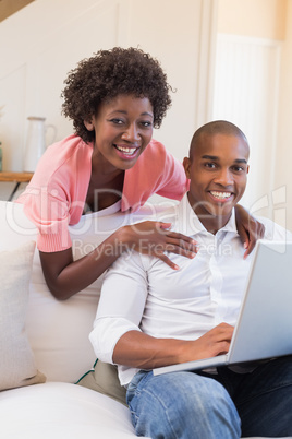 Cute couple relaxing on couch with laptop