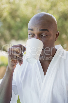 Handsome man in bathrobe having coffee outside