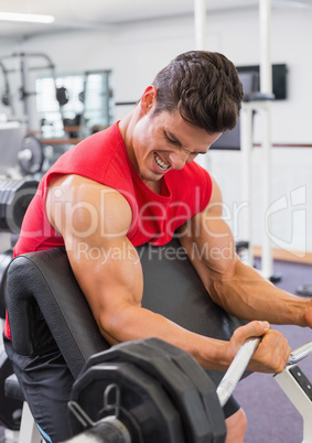 Muscular man lifting barbell in gym