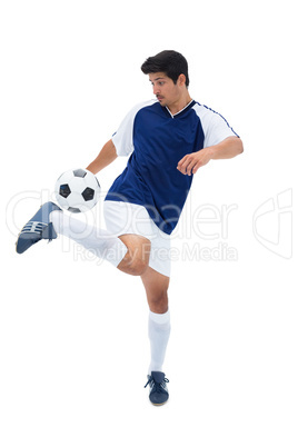 Football player in blue kicking ball