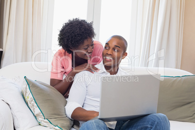 Cute couple relaxing on couch with laptop