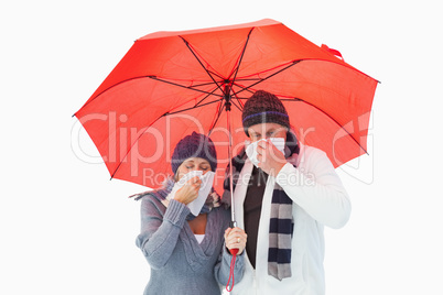Mature couple blowing their noses under umbrella