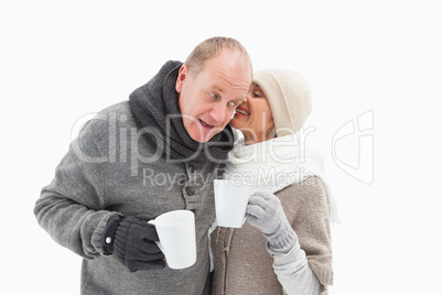 Happy mature couple in winter clothes holding mugs