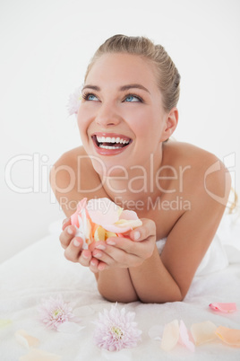 Pretty blonde lying on massage table holding petals