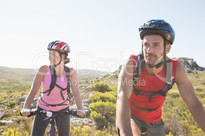 Fit cyclist couple riding together on mountain trail