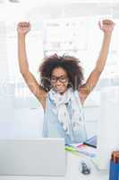 Pretty hipster cheering at her desk with laptop