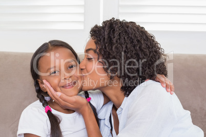 Pretty mother sitting on the couch with her daughter smiling at