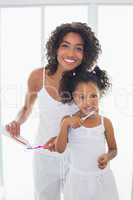 Pretty mother with her daughter brushing their teeth