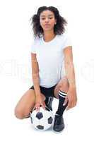 Pretty football player in white holding ball looking at camera
