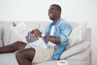 Casual man sitting on sofa reading the paper