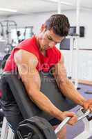 Muscular man lifting barbell in gym