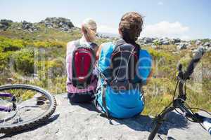 Fit cyclist couple taking a break on rocky peak