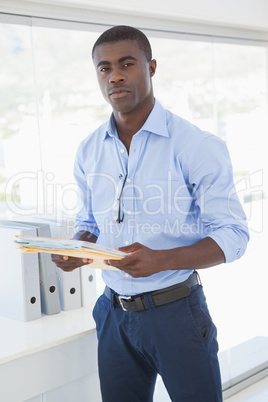 Serious businessman holding documents looking at camera