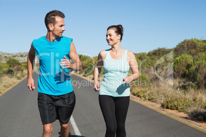 Fit happy couple jogging on the open road together