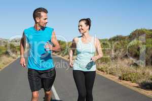 Fit happy couple jogging on the open road together