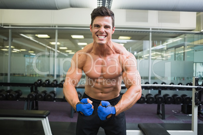 Shirtless muscular man flexing muscles in gym