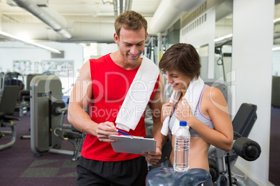 Handsome personal trainer with his client looking at clipboard