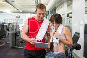 Handsome personal trainer with his client looking at clipboard