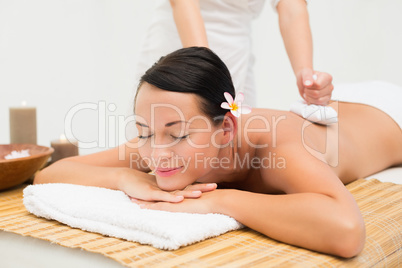 Peaceful brunette enjoying a herbal compress massage