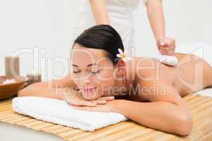 Peaceful brunette enjoying a herbal compress massage