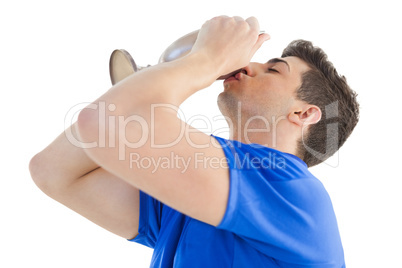 Football player in blue jersey kissing winners cup