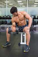 Muscular man exercising with dumbbell in gym