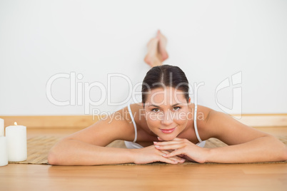 Smiling brunette lying on floor looking at camera