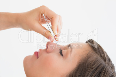 Close-up side view of hand plucking eyelashes