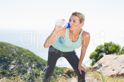 Fit blonde taking a break at summit drinking water