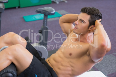 Muscular man doing abdominal crunches in gym