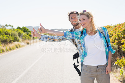 Attractive couple standing on the road hitch hiking