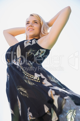 Pretty blonde in sundress standing with arms behind head