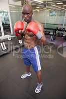 Muscular boxer in defensive stance in health club