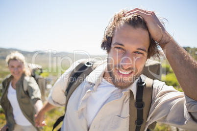 Hiking couple walking on mountain terrain smiling at camera