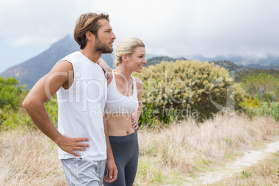 Attractive fit couple standing on mountain trail