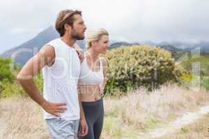 Attractive fit couple standing on mountain trail