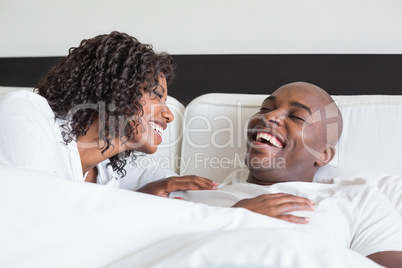 Happy couple cuddling in bed and laughing